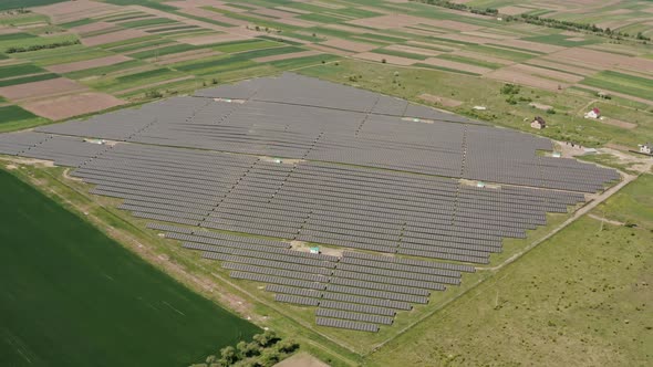 Aerial Drone View. Solar Power Plant Farm in Summer with Fields in the Background Production of