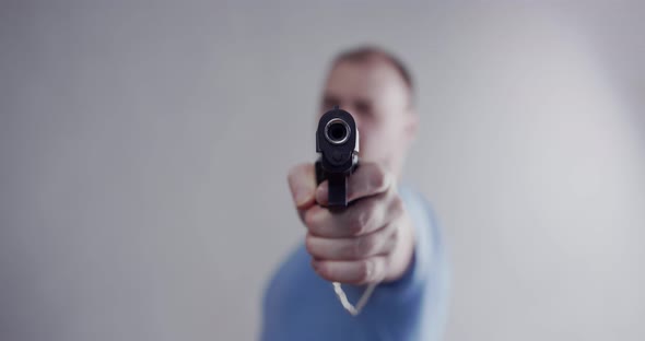 The man threatens with a pistol, points the pistol at the camera. Close-up barrel of a pistol.