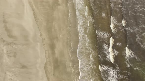 Aerial View of a Sandy Beach with Waves Coming From the Ocean.