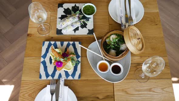 Lovely starters at trendy restaurant - dumplings, tempura prawns, springrolls_top-down crane shot