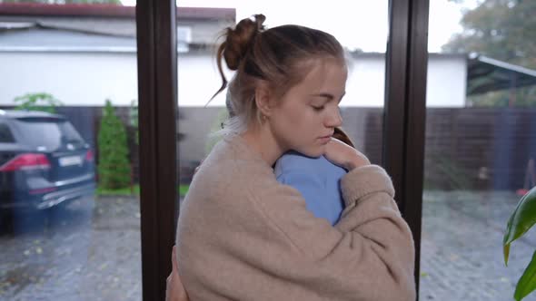 Side View Sad Teenage Girl and Woman Hugging at Window Indoors