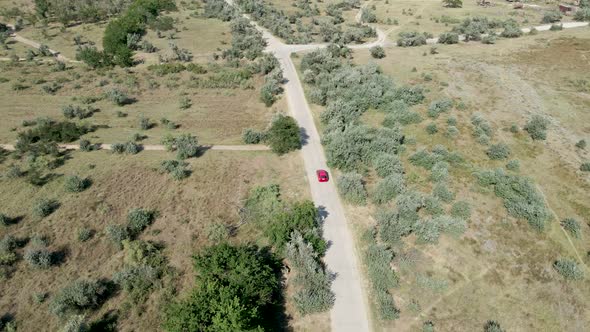 a Red Passenger Car Drives on a Shroud on a Concrete Road