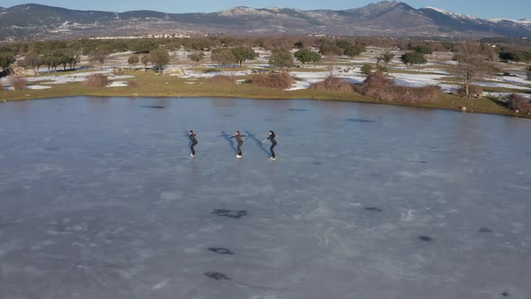 Three young women figure skating on frozen lake