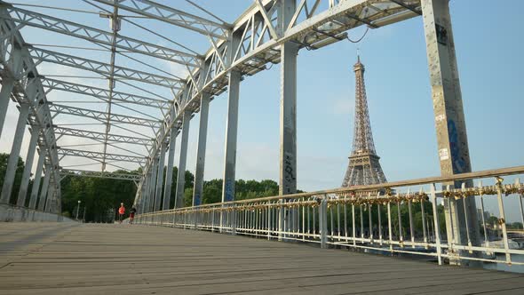 A couple running across a bridge with the Eiffel Tower
