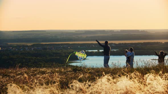 Young Family Playing with Kite on Sunset Wheat Field