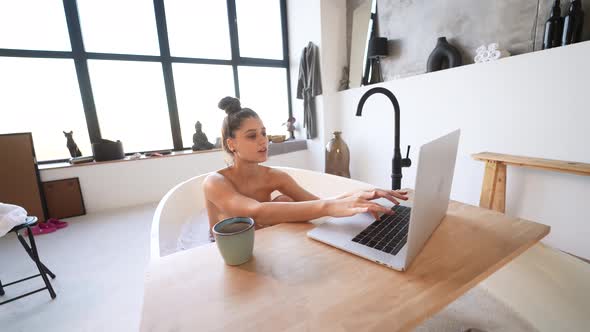 Young Woman Working on Laptop While Taking a Bathtub