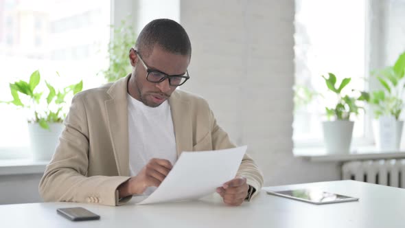 African Man Reading Papers While Sitting in Office