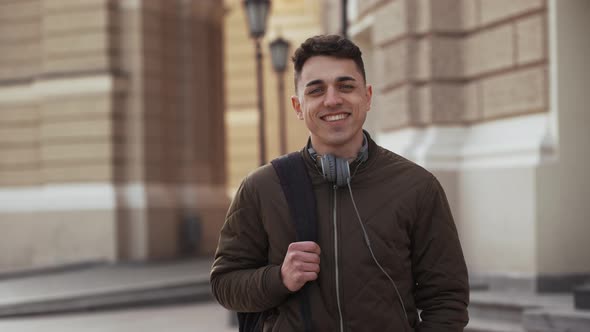 Portrait of Caucasian Young Man 20s Wearing Jacket Walking with Backpack After Study and Posing Over