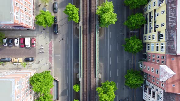 Pedestrians cross the street elevated train car passes. Unbelievable aerial view flight bird's eye v