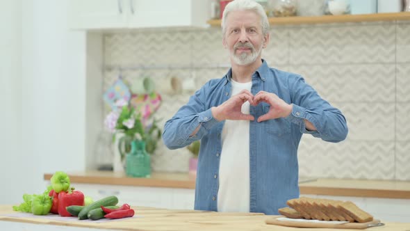 Loving Old Man Making Heart Shape By Hands While in Kitchen