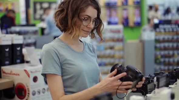 Young Woman in Glasses Shopping for a New Photocamera in the Electronics Store