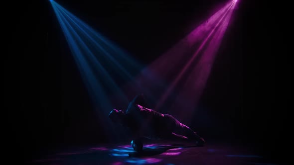 Silhouette of a Guy Performing Break Dance Tricks on the Floor. Sports Lifestyle. Indoor Dark Studio
