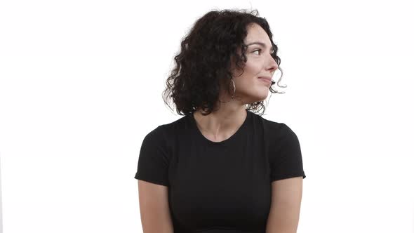 Attractive Young Woman with Dark Curly Hair Wearing Black Tshirt Looking Flirty and Smiling Turning