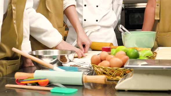 Chef stuffs and press pastry dough, making fruit pies in a restaurant kitchen.