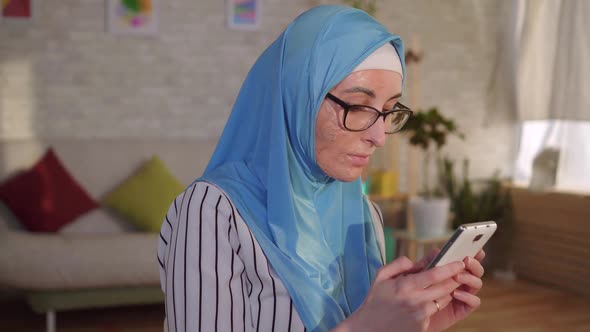 Portrait Young Muslim Woman in Hijab with a Scar From a Burn on Her Face Uses a Smartphone