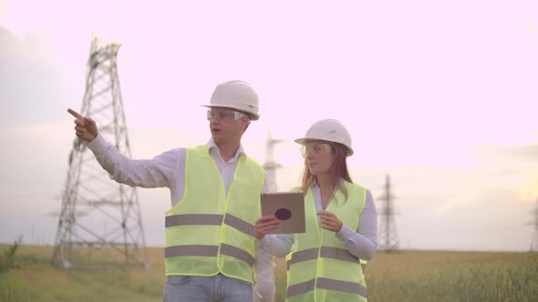 A Group of Engineers at a Highvoltage Power Plant with a Tablet and Drawings Walk and Discuss a Plan