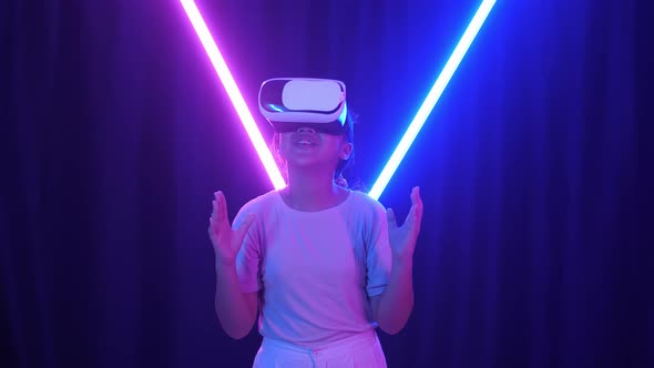 Excited Asian Young Girl Using Virtual Reality Headset With Neon Light At The Background