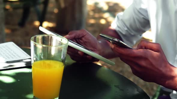 Mid section of man using digital tablet and mobile phone