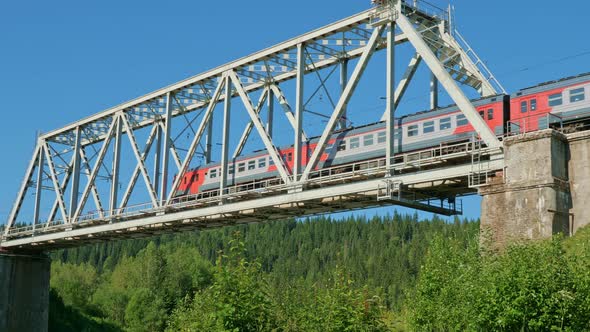 Passenger Train Rides Over Bridge in Wooded Area