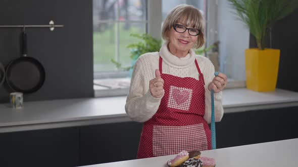 Portrait of Attractive Senior Woman Gesturing Thumb Up Smiling Looking at Camera Indoors