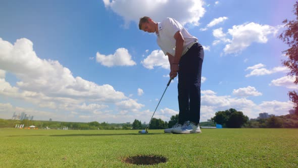 Professional Golfer Hits a Ball Into Hole on a Grass Field.