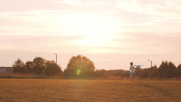 Little boy plays with a toy plane in a field at sunset. Childhood, freedom, inspiration concept.