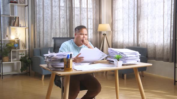 Fat Asian Man Yawning While Working Hard With Documents At The Office