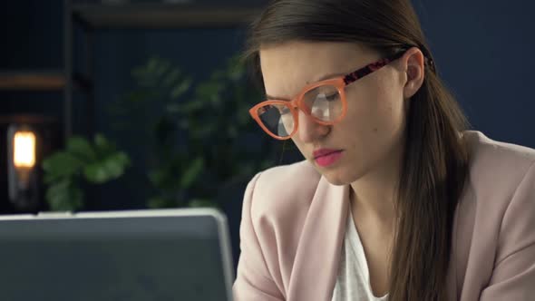 Close Up Portrait of a Beautiful Serious Woman in Glasses Working at a Laptop