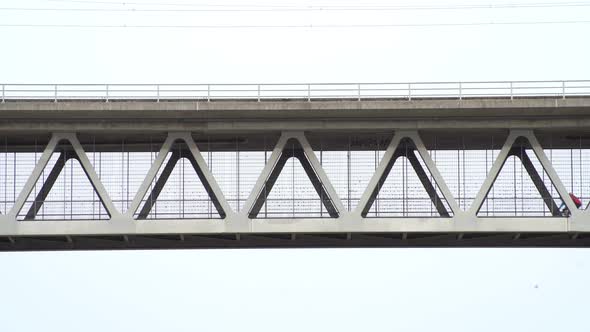 Two bike riding men driving from the right to the left over a steel construction bridge in the sky,