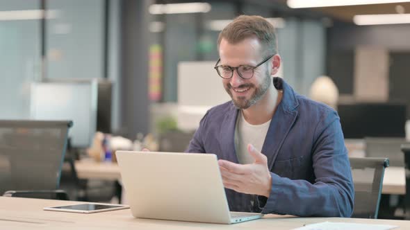 Middle Aged Businessman Celebrating While Using Laptop in Office