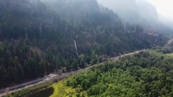 Drone shot of a road in the Columbia River Gorge with Horsetail Falls majestically cascading over th