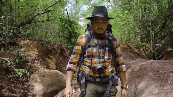 slow-motion of man traveler with backpack walking and looking in the natural forest