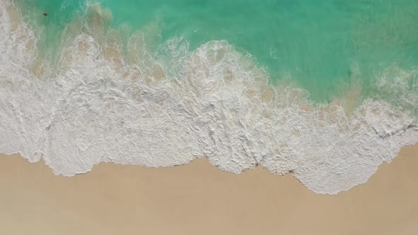 Top Down Aerial View of White Sand Beach with Azure Water Foaming Ocean Waves