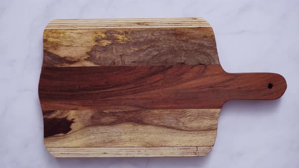 Rustic wood cutting board on marble countertop.