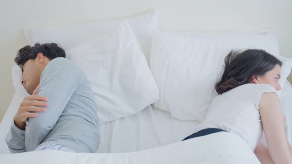 Asian young couple lying down on bed with painful after fight argument. Family problem-separation.