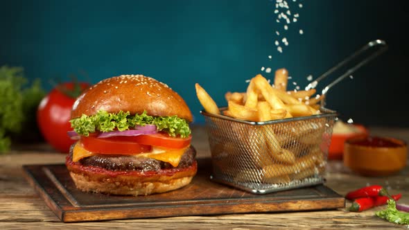 Super Slow Motion Shot of Falling Salt on Fresh Freench Fries Next to the Hamburger at 1000Fps