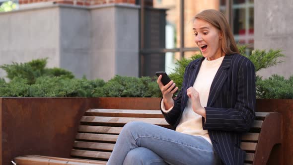 Business Woman Celebrating Success While Using Smartphone