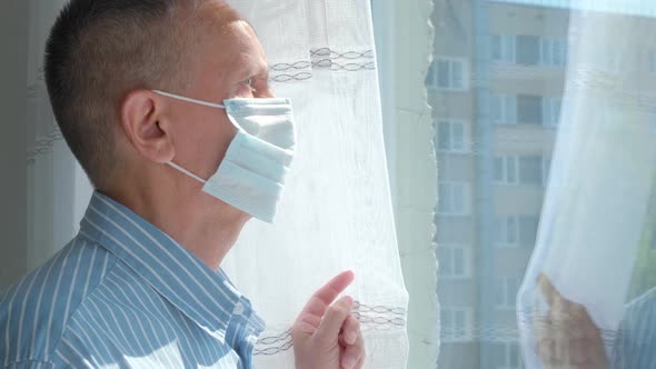 Elderly Man on Selfisolation Looks at the Street Through the Window of House