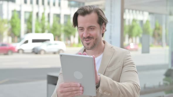 Young Man Celebrating Online Win on Tablet Outdoor