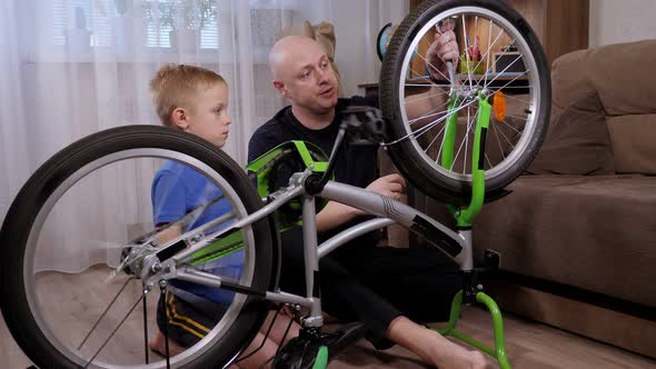 Portrait of a Young Father and His Son Repair a Broken Bicycle Together at Home