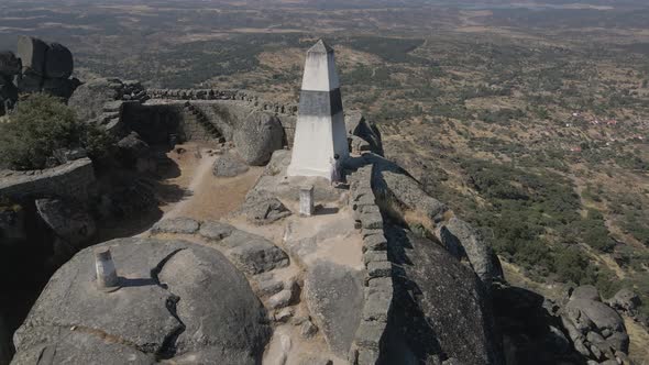 Woman greets drone from fortification of Monsanto Castle and walking on walls, Portugal. Aerial orbi