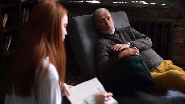 Attractive Young Woman with Red Hair Psychologist Holding Consultation with Mature Bearded Man