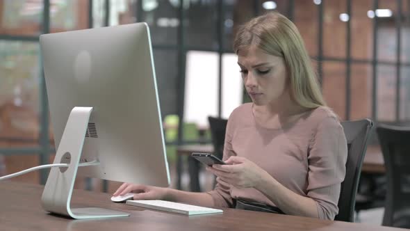 Young Woman Using Cellphone While Sitting on Office Desk