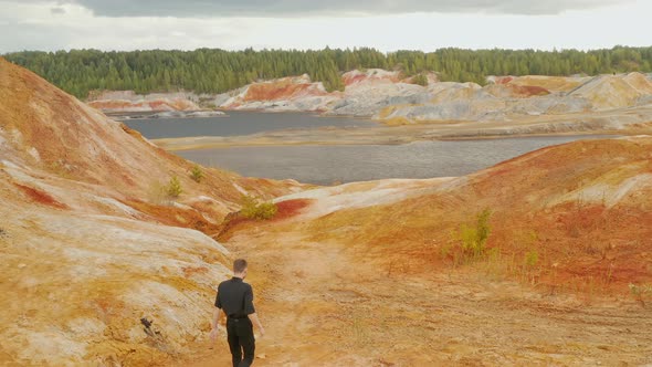 A man is walking on an orange clay valley Colorful slopes Ural Mars