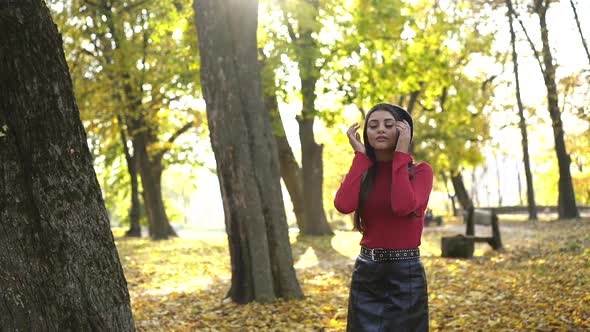 Young Brunette in Stylish Look Posing with Smile at Camera in Sunny Autumn Park