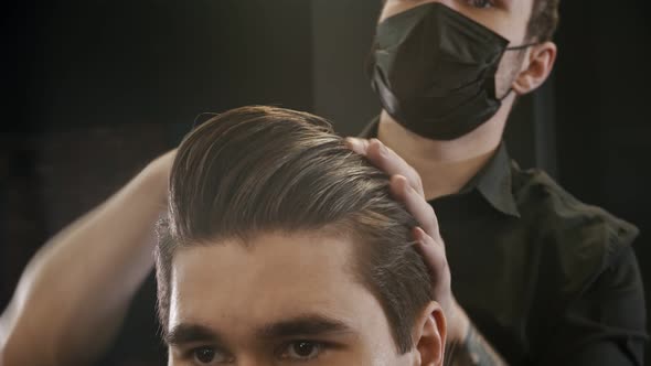 Barber in Black Mask Styling His Client Hair Using a Gel