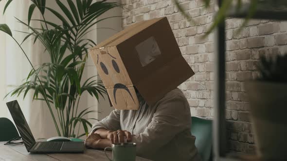 Sad people working on laptop wearing paper box on his head. Concept of stress and privacy issue web