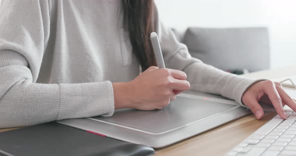 Designer working on drawing pad and computer at home