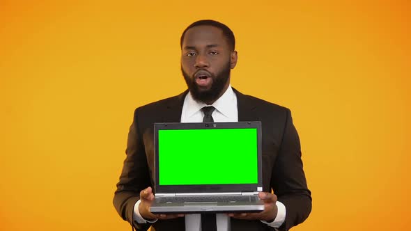 Afro-American Male in Formal Suit Holding Prekeyed Laptop and Smiling, Wow