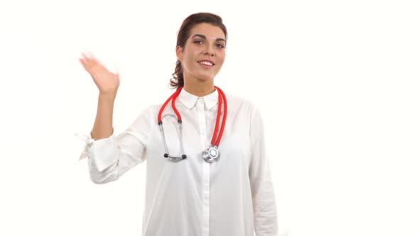 Young Female Doctor Waving Her Hand Smiling Friendly Crossing Arms and Looking at Camera